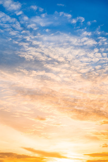 美丽奢华的柔和渐变橙金色云彩和阳光映衬在蓝天上，完美适合作为背景，拍摄于傍晚黄昏，超大尺寸，高分辨率风景照片，竖版。图片下载