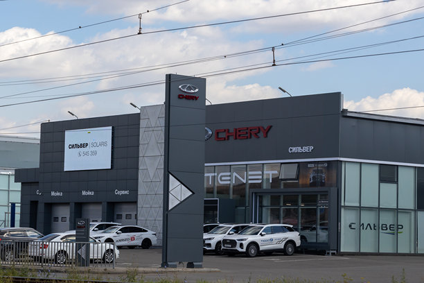 奇瑞汽车经销商外观展示多款车辆和标识，突显现代建筑和品牌形象，位于充满活力的城市环境中图片下载