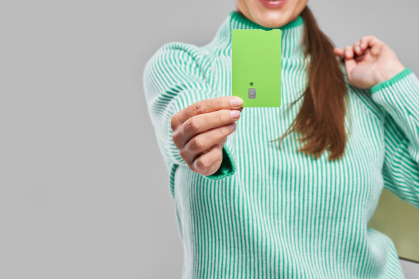 背景中有女性手持绿色信用卡和购物袋的照片图片下载