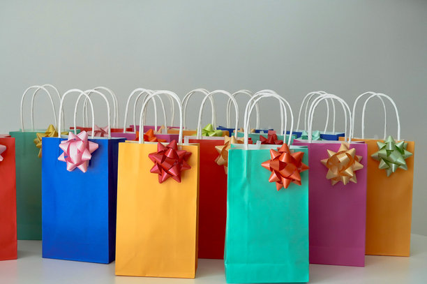 五颜六色的购物袋上系着丝带，背景为白色，库存照片图片下载