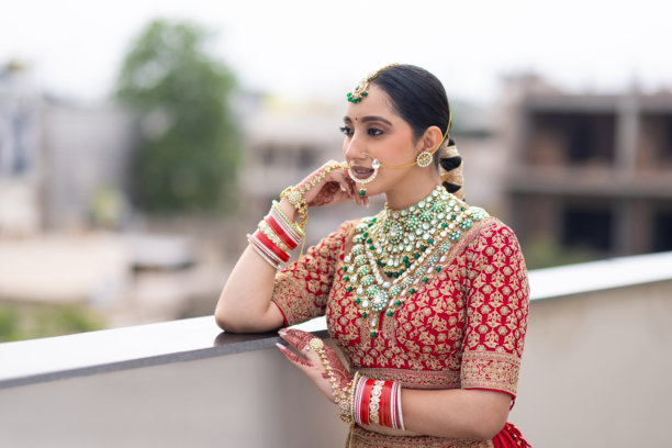 非常美丽的年轻印度新娘在户外穿着奢华的婚礼服装，化着妆，佩戴着华丽的珠宝的肖像照片图片下载