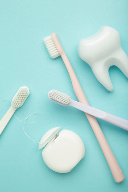 健康的牙科护理工具。蓝色背景上的塑料牙齿、牙线和牙刷。竖版照片。图片下载