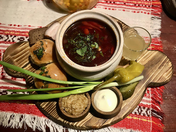 传统红菜汤在锅中，配有青葱、培根、面包饺子，旁边是一杯白酒，放在餐厅的木托盘上。图片下载