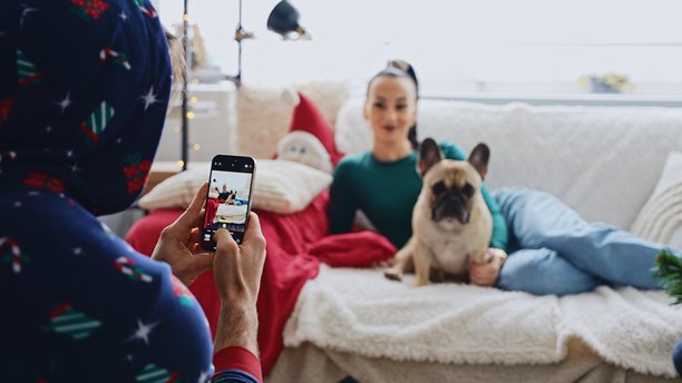 男人在沙发上给女人和狗拍圣诞照片图片下载