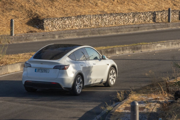 电动特斯拉汽车在风景如画的乡村道路上行驶图片下载
