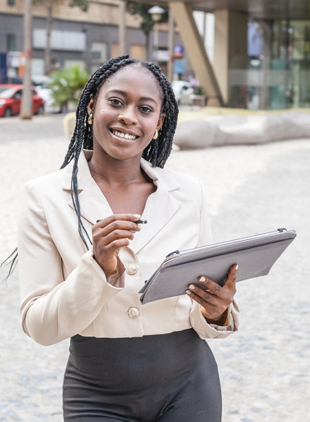 非裔美国女商人在商务环境中微笑着使用平板电脑。竖版照片图片下载