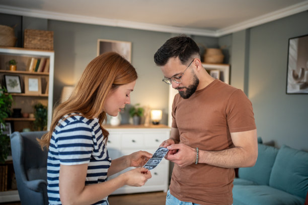 年轻夫妇在家中拿着超声波扫描照片图片下载