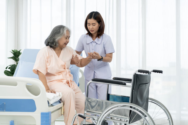 一名护士把一名亚洲老人扶上轮椅，带他去给他在事故中受伤的腿拍x光片。图片下载