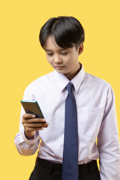 短发女学生在黄色背景下使用智能手机的照片图片下载