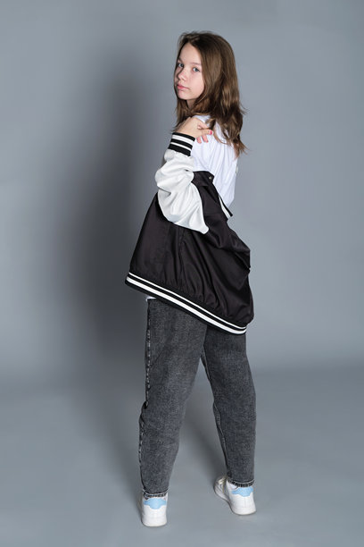 年轻女孩侧身站立，柔和地凝视着，外套随意披在身上。这张图片突显了自然、毫无防备的瞬间之美，常见于当今的生活方式肖像中。图片下载