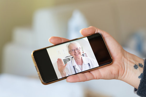 手握智能手机，屏幕上显示医生的视频通话照片图片下载