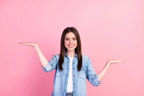 女性学生在粉色背景下微笑，手中比较空白区域的照片肖像。图片下载