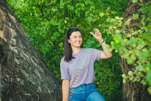 女人在森林里玩塑料弹簧玩具的照片图片下载