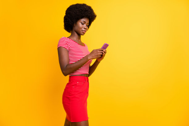 专注的漂亮深肤色人士在黄色背景下使用手机撰写帖子的人像照片图片下载