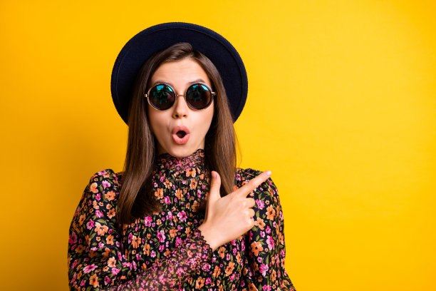 惊讶的人物肖像，指着空白处，张嘴，佩戴复古风格的头饰，背景为黄色。图片下载