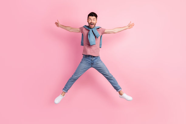 活泼快乐的年轻男孩在粉色柔和背景上跳起星星形状的全身照片图片下载