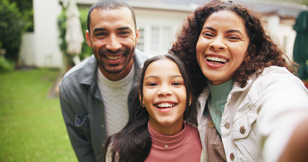 快乐的父母与女孩在新家后院自拍，记录社交媒体上的美好回忆。家庭肖像，妈妈、爸爸和孩子在户外的照片，展现亲密关系和支持。图片下载