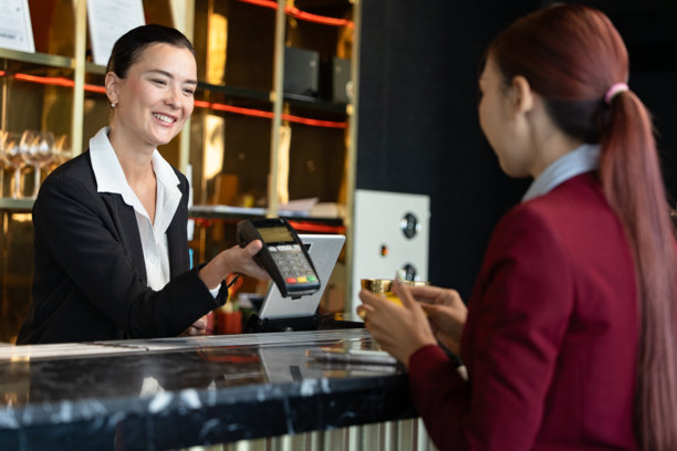 迷人的女销售员，收银员手持信用卡读卡器为顾客服务，并在零售店柜台或酒吧餐厅柜台上持有信用卡。图片下载
