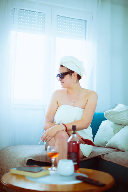 年轻女性穿着毛巾，戴着太阳镜，抽着香烟的照片图片下载