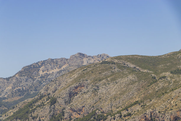 西班牙瓜达莱斯附近壮丽的山地风光，展现了崎岖的地形和丰富的植被，在晴朗的蓝天下，突显了自然之美和户外探险的机会。图片下载