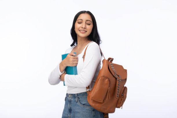 年轻女学生背着书包，穿着现代服装，独自站在白色背景前的照片图片下载