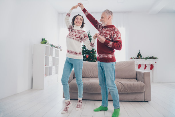 穿着毛衣、牛仔裤和袜子的搞笑老年夫妇在家中跳舞的全身照片图片下载