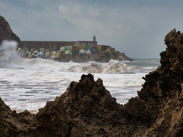 暴风雨中的海浪撞击岩石码头 - 一张戏剧性的长时间曝光照片，展现强大的海浪在暴风雨的日子里撞击码头，五彩斑斓的防波堤块映衬其间。图片下载