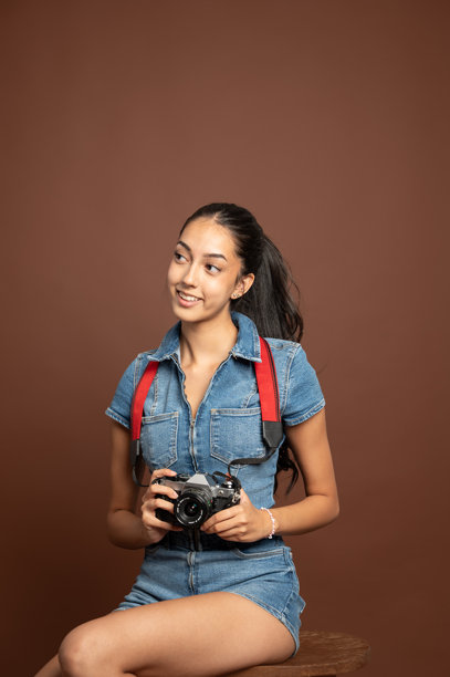 年轻摄影师手持复古相机，微笑着思考下一张照片，留有空白空间。图片下载