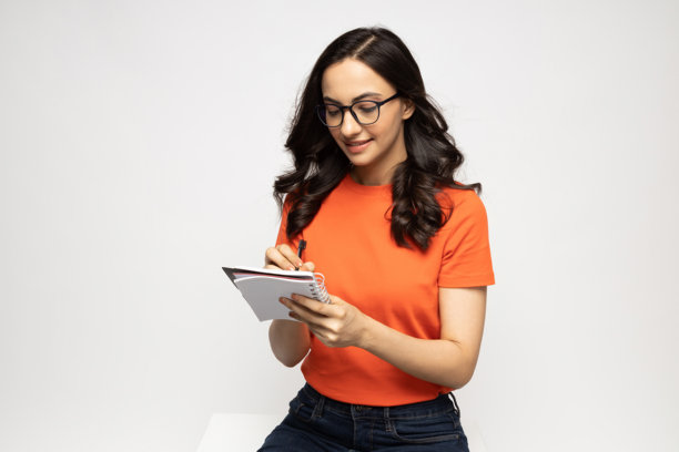 自信的年轻女性手持笔记，背景为白色背景的隔离照片图片下载