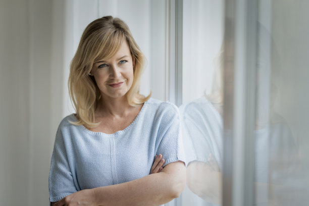 一位金发女性站在窗边的照片图片下载