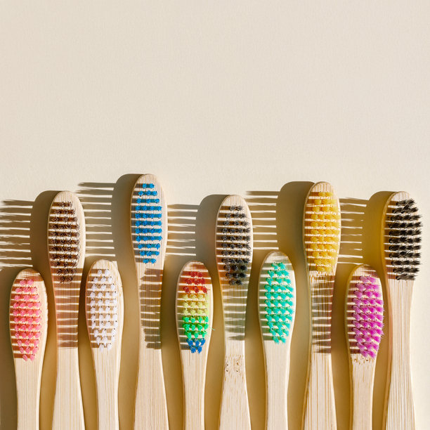 阳光下的米色背景上，特写的米色竹牙刷，刷毛呈现多种颜色。简约、卫生和环保的替代品，俯视照片，极简风格平铺。图片下载