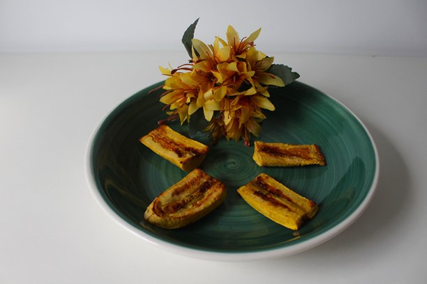 横向照片。绿色盘子上的熟香蕉与黄色花朵。白色背景，俯视图，留有文字空间。图片下载