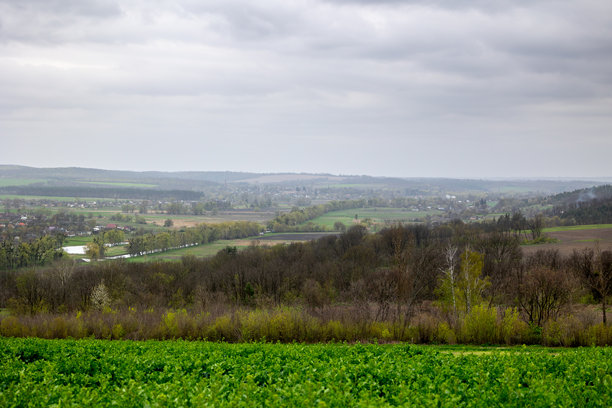 乌克兰切尔卡瑟地区Mliyiv村的春季四月底景观，位于维尔尚卡河谷。照片展示了被绿色田野和起伏山丘环绕的房屋和建筑。图片下载