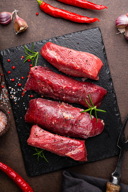 生牛肉牛排。新鲜的农场牛排上撒有迷迭香、盐和胡椒，放在黑色板子上，背景为深色。生牛肉牛排和烹饪香料的俯视垂直照片。图片下载