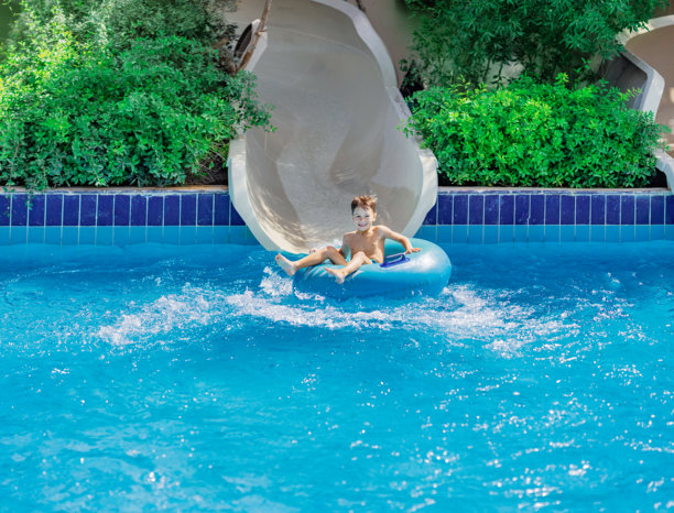 埃及赫尔格达的照片，年轻男孩在滑水道后在泳池中玩耍图片下载