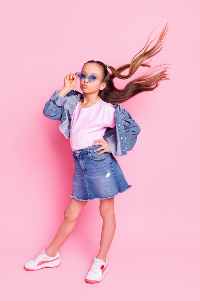 全身竖版照片，阳光开朗的女孩穿着牛仔裤，背景为粉色。图片下载