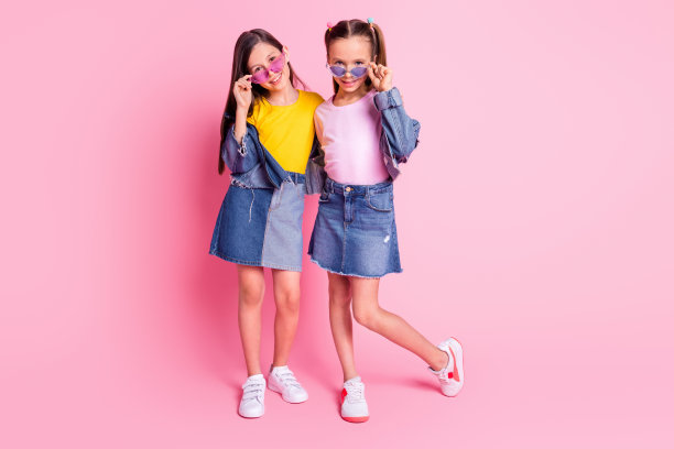 乐观的棕发和金发女孩穿着黄色和粉色T恤裙，在粉色背景下拥抱的全身照片图片下载