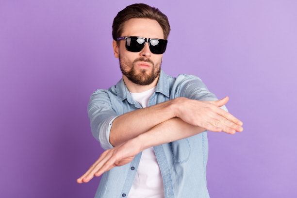 穿着牛仔衬衫、戴着深色眼镜的搞笑酷炫年轻男子在紫色背景下跳舞的照片图片下载