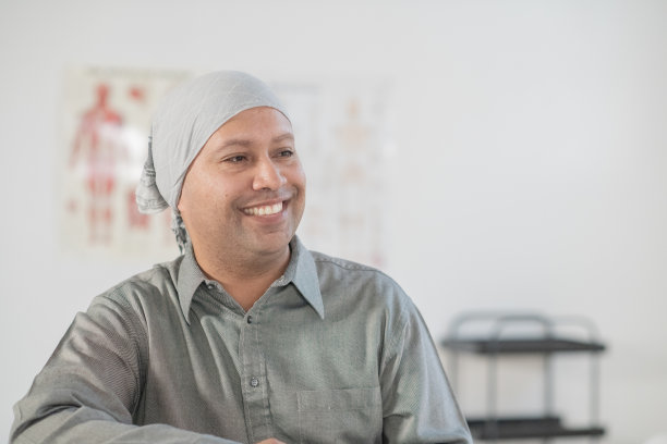 微笑的男子在医疗环境中佩戴医用头巾，适合健康护理的库存照片图片下载