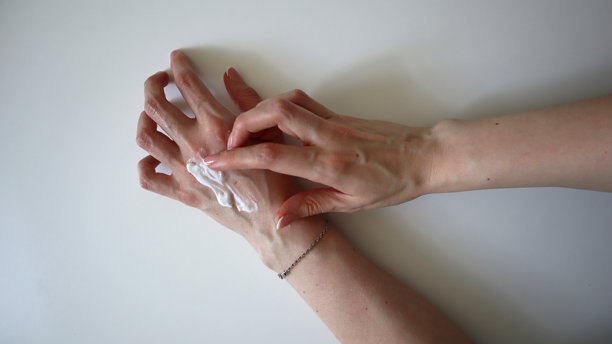手部护肤。女性的手。一只手在另一只手上涂抹护肤霜。护肤霜、防晒霜、面膜等。白色背景。照片。图片下载