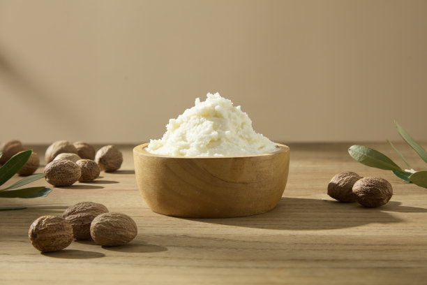一个干净的构图，包含一碗乳木果油和散落的坚果。简约自然的护肤氛围。适合用于乳木果油成分的广告照片。图片下载