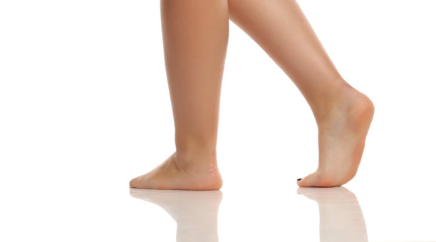 女性赤脚踮起脚尖在白色背景上行走的侧面照片。图片下载