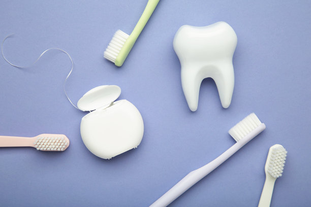 健康的牙科护理工具。紫色背景上的塑料牙齿、牙线和牙刷。竖版照片。图片下载