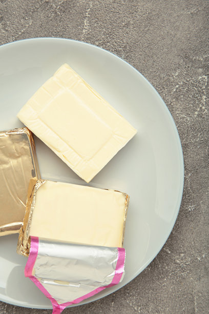 灰色盘子上的铝箔加工奶酪，背景为灰色混凝土。竖版照片图片下载