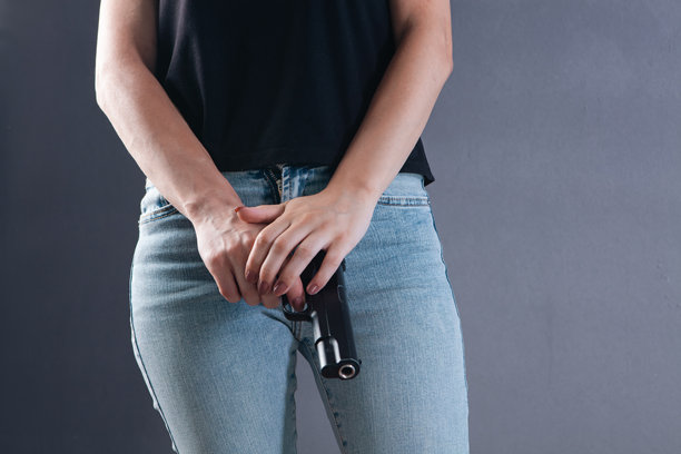 女人手持枪支的特写。背景为灰色。图片下载