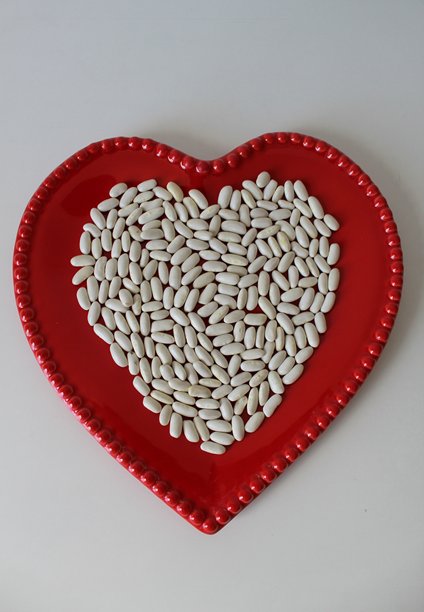 心形碗中的生白豆。周围有空白空间。健康食品质感。竖版照片图片下载