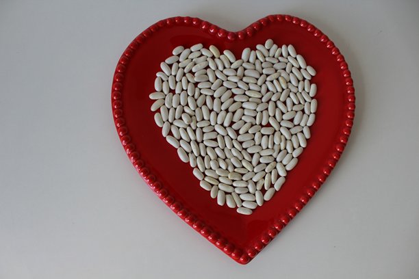 横向照片。年轻的新鲜白豆放在红色陶瓷碗中。背景为白色。俯视图。左侧留有空白。图片下载