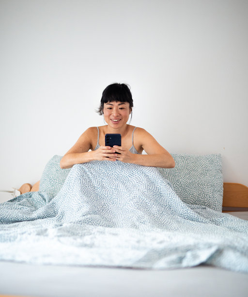 在家床上微笑使用手机的女性 - 股票照片图片下载