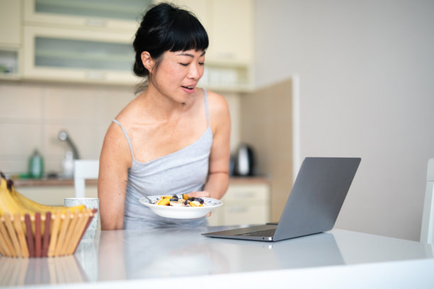 在厨房吃早餐时在家工作的女性 - 股票照片图片下载