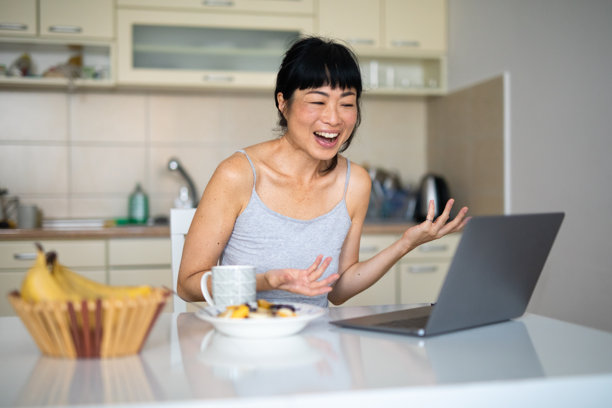 亚洲女性在厨房吃早餐时进行视频通话 - 股票照片图片下载